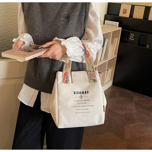 Detail of cream canvas bucket bag featuring floral woven handles and printed lifestyle text