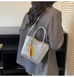 Detail showing metallic silver tote bag with textured finish and colorful bead charm