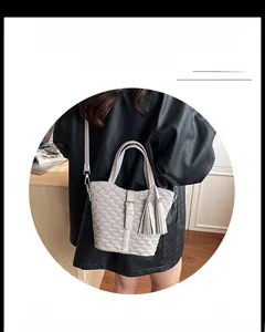Detail of cream pleated bucket bag with tassel charms and adjustable shoulder strap