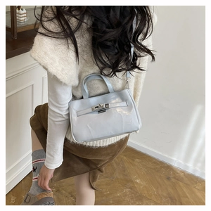 Détail du sac seau en cuir verni bleu clair avec boucle argentée et bandoulière