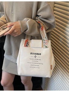 Minimalist cream canvas bucket bag with floral jacquard straps and printed slogan