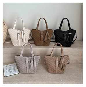 Detailed view of woven bucket bags in five colors with tassel charms and metallic accents