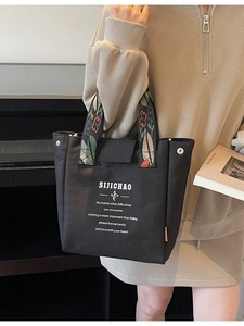 Minimalist black canvas tote bag with colorful floral woven handles and stylish print