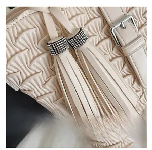 Detail of pleated faux leather handbag featuring silver rhinestone tassels and buckle strap