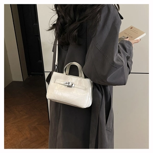 Détail du sac seau blanc avec sangle et fermoir rotatif argenté sur manteau