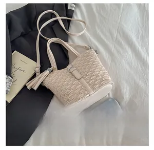 Detail of cream pleated bucket bag showing fine texture and stylish tassel ornament