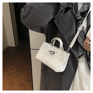Détail d'un sac seau blanc à motif crocodile avec fermoir rotatif en métal doré