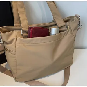 Détail du sac fourre-tout en nylon kaki montrant le rangement du portefeuille et du thermos