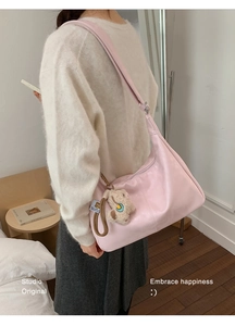 Detail of pink hobo bag with cute plush bear charm and silver zipper in home setting