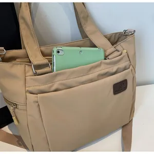 Gros plan d'un cabas en nylon kaki avec poche avant pour tablette et étiquette en cuir