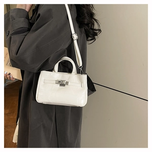 Détail du sac seau blanc brillant avec fermoir rotatif argenté et poignée chic
