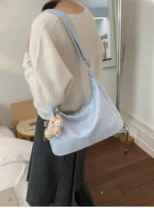 Close-up of light blue soft leather tote bag with a cute sheep plush toy accessory