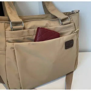 Détail du sac cabas en nylon beige montrant une poche avant avec un portefeuille matelassé