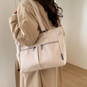 Detail of canvas tote bag showing side pockets, zipper design, and durable texture