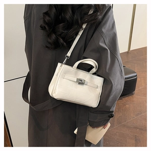 Détail du sac en cuir blanc avec fermoir rotatif argenté et texture à grain fin