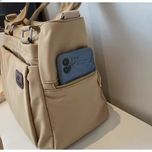 Gros plan du sac cabas en nylon kaki avec poche latérale zippée et étiquette logo en cuir