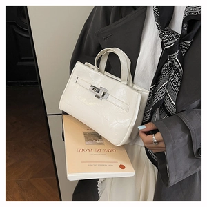 Gros plan d'un sac seau en cuir verni crème avec texture brillante et boucle métal