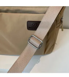 Détail de la bandoulière réglable et boucle en métal d'un sac cabas en nylon kaki
