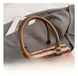 Detail showing the brown leather handle and pink striped plush fabric of the tote bag