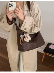 Detail of soft brown pebble leather hobo bag with a cute plush bear charm accessory