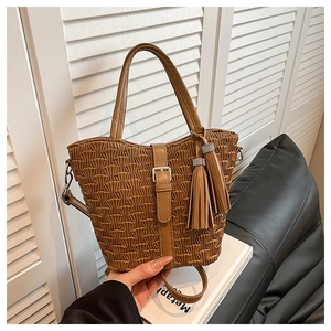 Detailed view of brown ruched leather handbag with decorative tassels and buckled strap