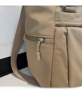 Détail d'une fermeture éclair en métal argenté avec tirette tressée sur un sac kaki
