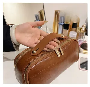 Detail of brown crocodile pattern cosmetic bag with gold studs and zipper closure