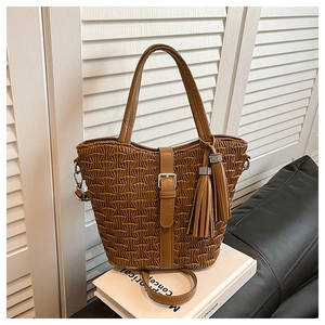 Close-up of brown woven texture bucket bag with fringe tassels and metal ring detail