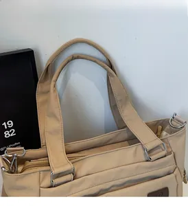 Gros plan d'un sac cabas beige avec poignées renforcées et anneaux en métal durables
