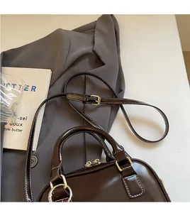 Detail view of a chocolate brown shell bag with gold hardware and fine stitching