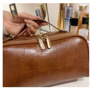 Detailed close-up of brown crocodile texture travel bag with smooth golden double zippers