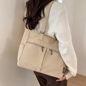 Detail view of beige canvas tote bag with functional double front zipper pockets