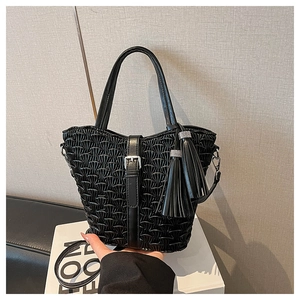 Detailed view of black pleated texture handbag with silver buckle and tassel accents