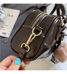 Detail of dark brown glossy leather handbag with gold hardware and contrast stitching