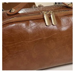 Detailed view of brown crocodile texture leather and premium gold metal zippers