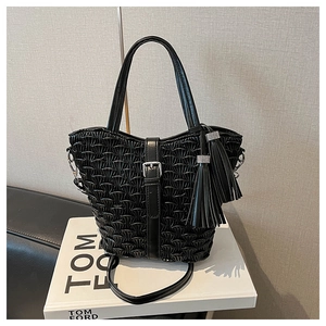 Close-up of black quilted bucket bag with decorative buckle and tassel details