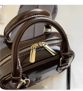 Detail of smooth double zipper closure and gold hardware on dark brown shell bag