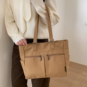 Khaki canvas tote bag detail featuring functional front zipper pockets and side compartments