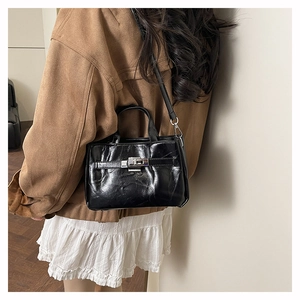 Vue latérale d'un sac seau en cuir verni noir porté par un mannequin en tenue chic