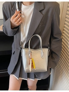 Silver metallic tote bag with pleated texture and beaded tassel charm on a shoulder strap