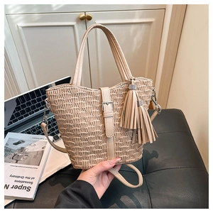 Detail of beige pleated bucket bag with tassel charm and silver buckle accent