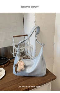 Detail of light blue crescent hobo bag with leather texture and cute alpaca pendant