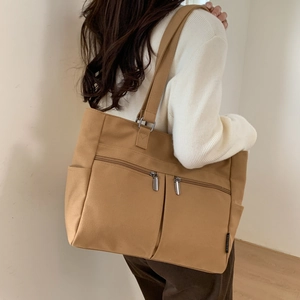 Detail of khaki canvas tote bag showing functional multi-pockets and side storage pockets