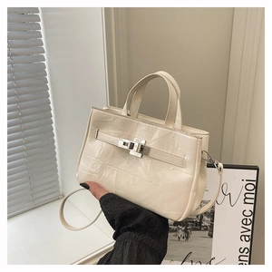 Détail d'un sac seau crème avec texture en cuir plissé et boucle métallique argentée