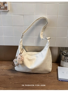 Close-up of white retro faux leather hobo bag with adjustable strap and plush charm