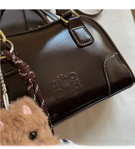 Close-up of dark brown Boston bag featuring contrast white stitching and embossed logo