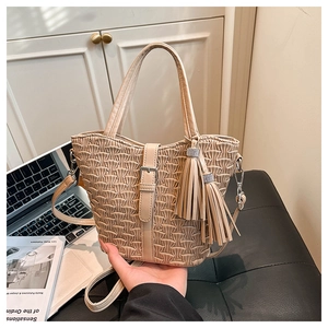 Detail of beige bucket bag featuring vertical pleated texture and large tassel charm