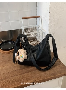 Detail of black pebbled leather hobo bag featuring a cute cream lamb plush charm pendant