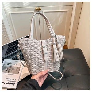 Detail of beige pleated bucket bag with tassel charms and long strap for crossbody wear