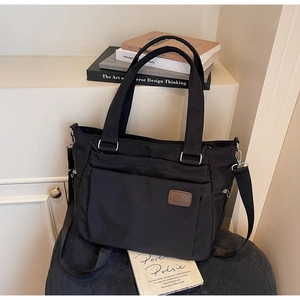 Detail of black nylon tote bag with multiple pockets and adjustable shoulder strap
